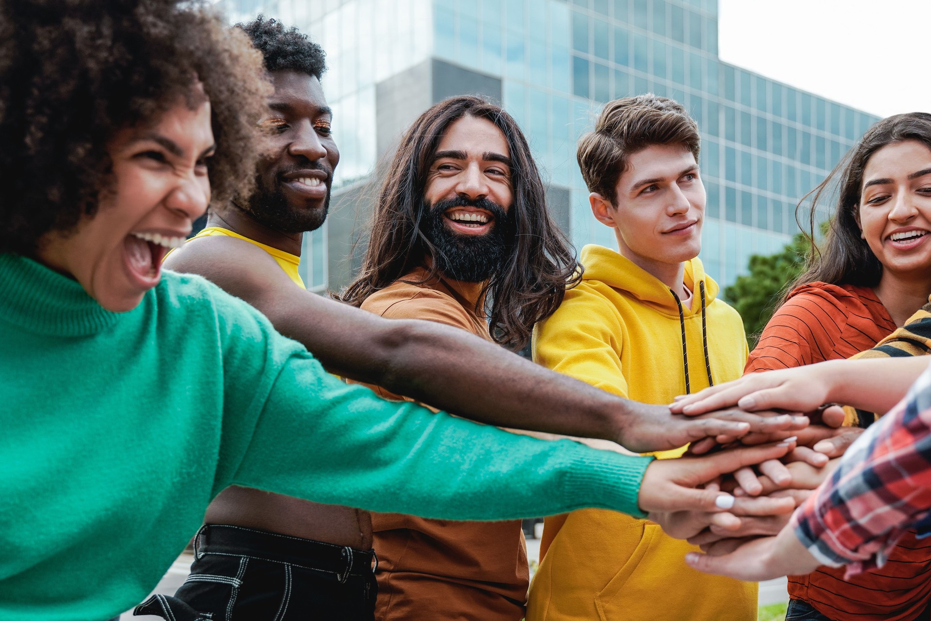 Young diverse group of people stacking hands together outdoor - Diversity team concept